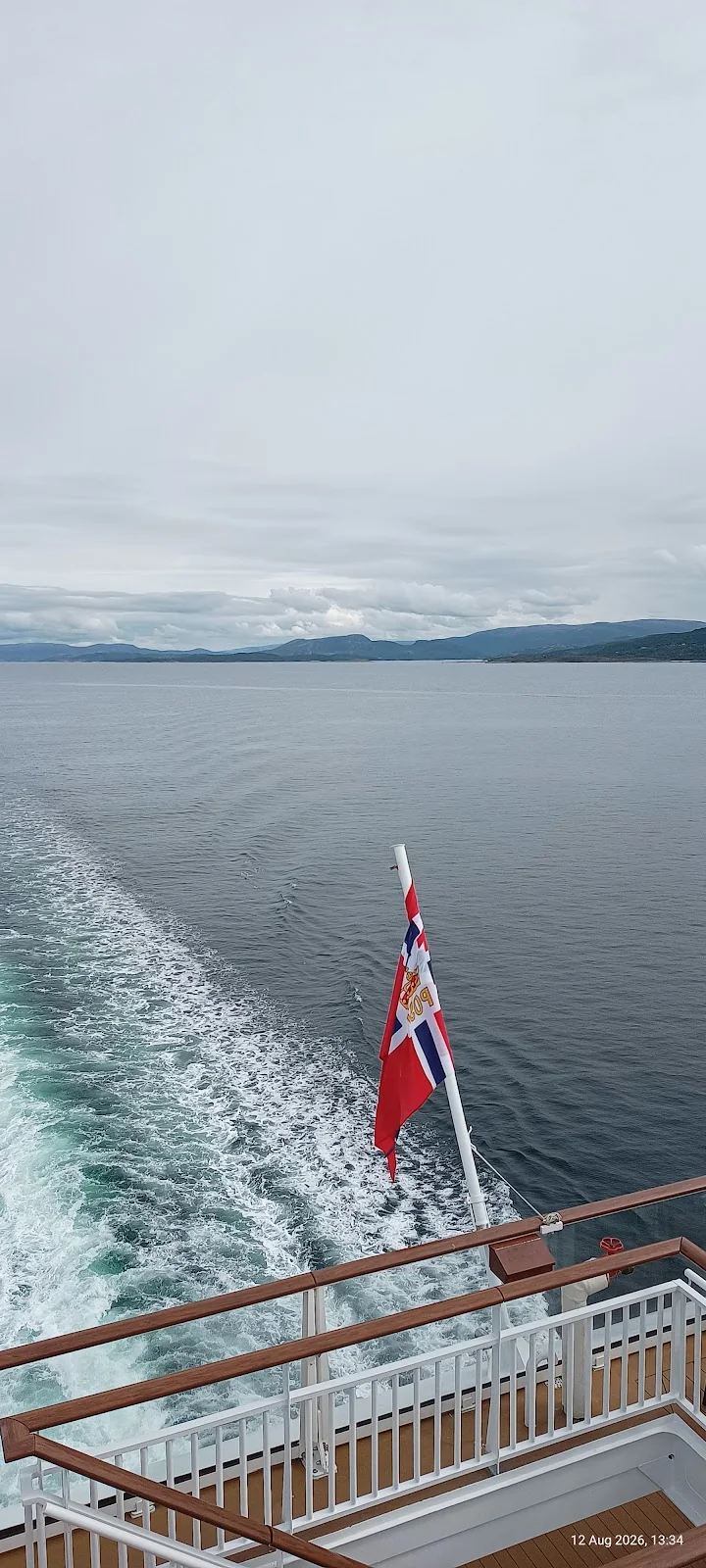 Norwegische Flagge am Heck einer Fähre, dahinter das Kielwasser
